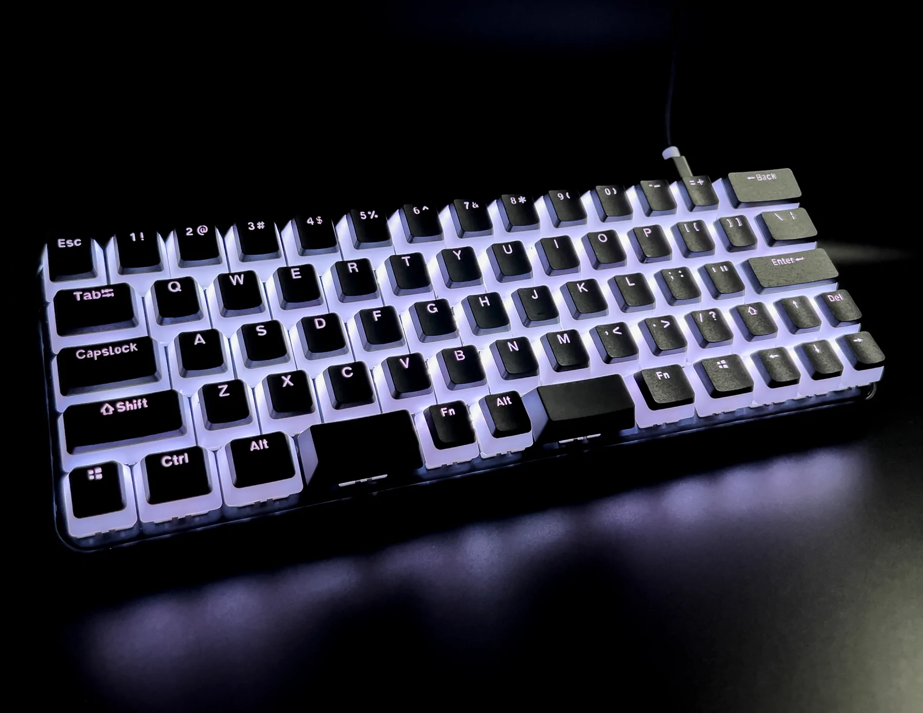 A promotional photograph of a keyboard called the Charachorder Lite. The keyboard has black keys with a white underglow.